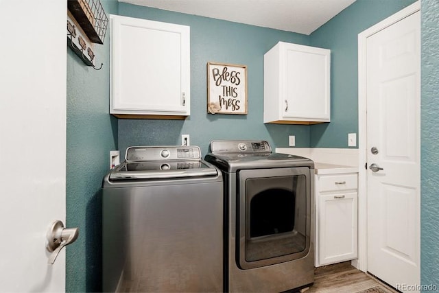 laundry room with light hardwood / wood-style floors, independent washer and dryer, and cabinets