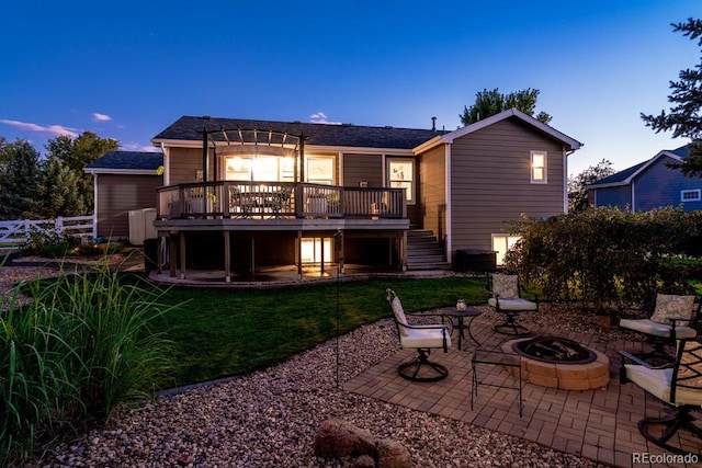 back house at dusk with a patio area, an outdoor fire pit, a deck, and a yard