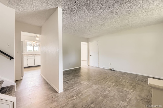 11310 W 46th Ave, Wheat Ridge, CO 80033 - empty room with stairway, a textured ceiling, baseboards, and a sink