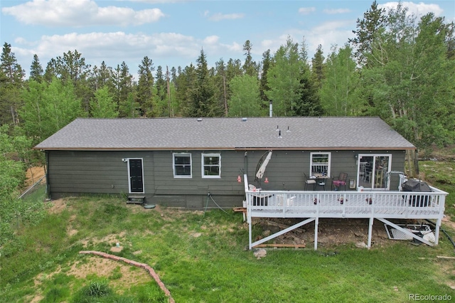 1021 Lodge Pole Dr, Black Hawk, CO 80422 - back of property featuring a wooden deck, a lawn, a shingled roof, and a wooded view