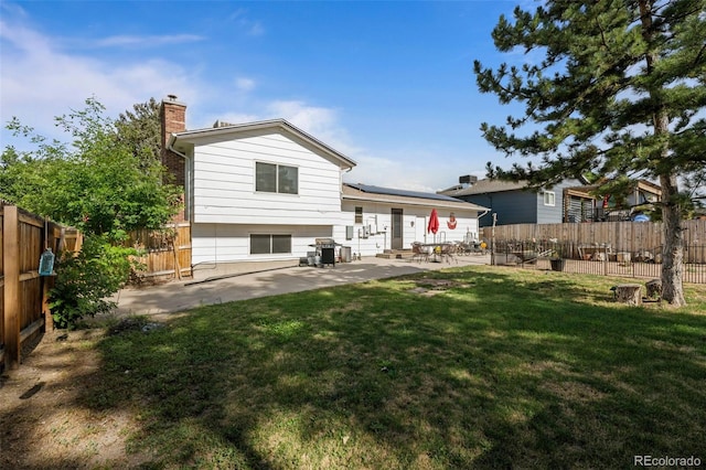 4501 S Garrison St, Littleton, CO 80123 - rear view of property with a patio area, roof mounted solar panels, a chimney, and a fenced backyard