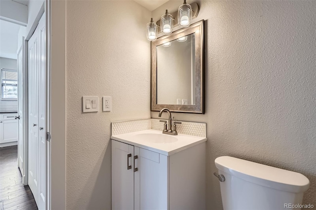 9605 E Kansas Cir Unit 53, Denver, CO 80247 - half bath featuring toilet, a textured wall, vanity, and wood finished floors