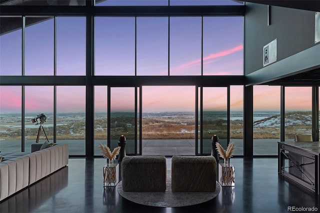 living room featuring concrete flooring, a wall of windows, and a water view