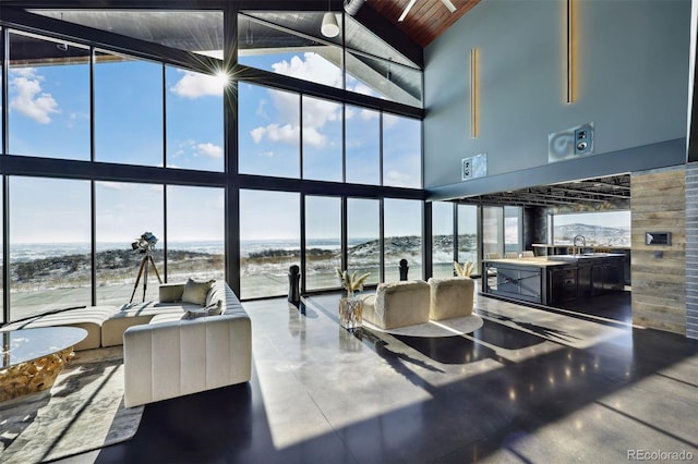 kitchen with wood walls, a water view, a sink, wood ceiling, and expansive windows