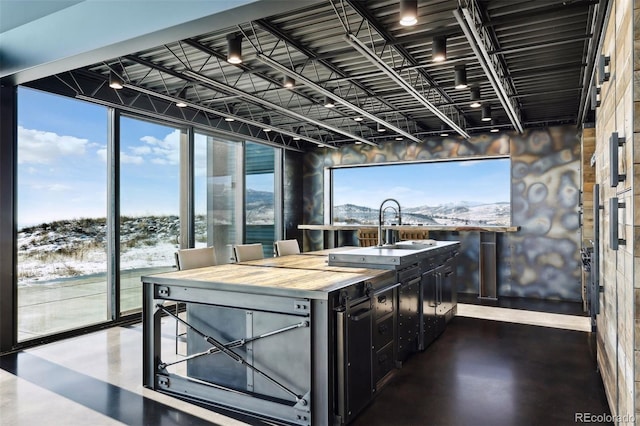 kitchen with floor to ceiling windows, a mountain view, a sink, dark cabinets, and concrete floors