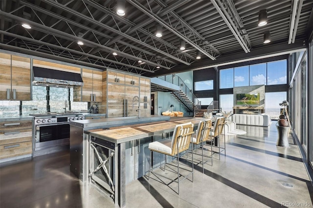 kitchen featuring butcher block counters, a kitchen island, modern cabinets, a kitchen breakfast bar, and extractor fan