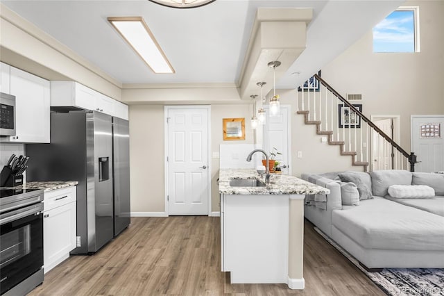 21535 E 39th Ave, Denver, CO 80249 - kitchen with light wood-style floors, stainless steel appliances, open floor plan, white cabinetry, and light stone countertops