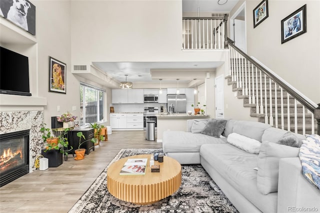 21535 E 39th Ave, Denver, CO 80249 - living room with a tray ceiling, light wood-type flooring, stairs, and a fireplace