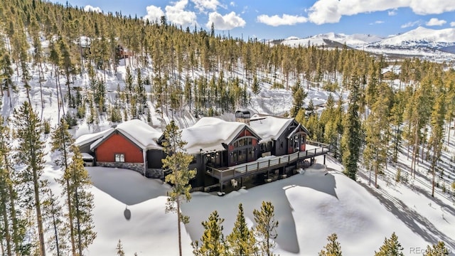 snowy aerial view with a mountain view and a wooded view