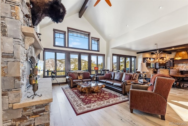 living room with hardwood / wood-style flooring, a fireplace, high vaulted ceiling, beam ceiling, and ceiling fan with notable chandelier