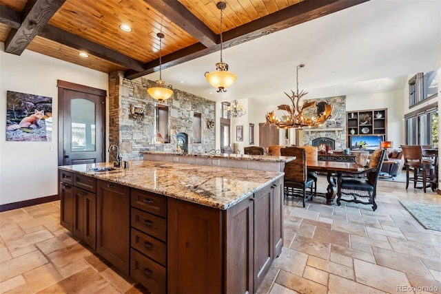 kitchen featuring open floor plan, wooden ceiling, a sink, and stone tile floors