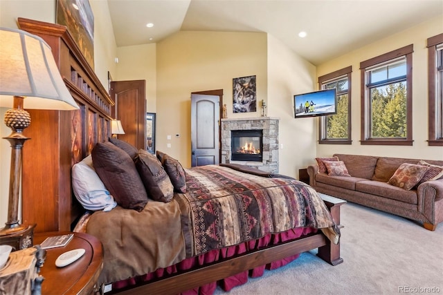 carpeted bedroom with high vaulted ceiling, a stone fireplace, and recessed lighting