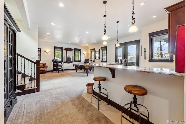 kitchen featuring light carpet, light stone countertops, decorative light fixtures, and recessed lighting