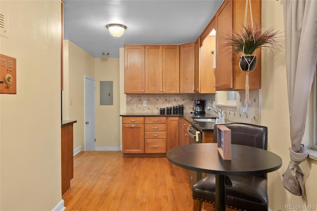 kitchen featuring sink, tasteful backsplash, light wood-type flooring, electric panel, and dishwasher