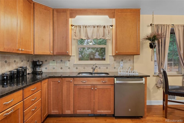 kitchen featuring sink, dishwasher, hardwood / wood-style flooring, dark stone counters, and backsplash