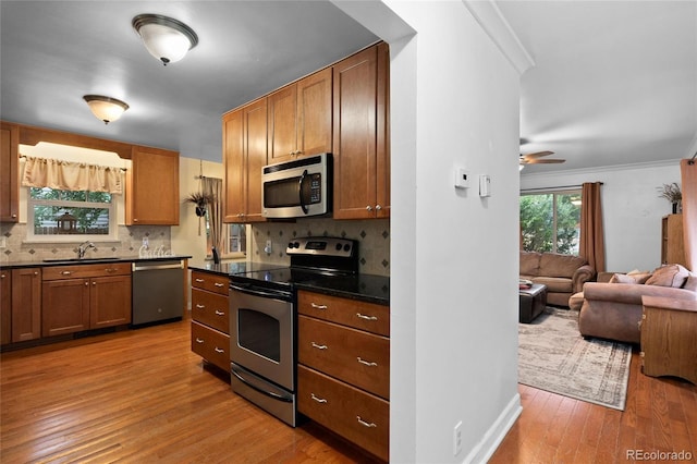 kitchen with appliances with stainless steel finishes, sink, decorative backsplash, light hardwood / wood-style floors, and crown molding