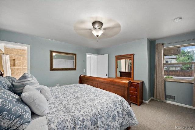 bedroom featuring connected bathroom, light colored carpet, and ceiling fan