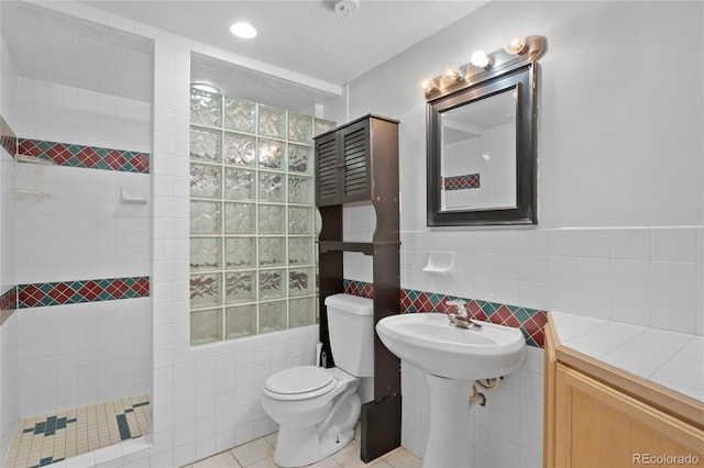 bathroom with tile patterned flooring, a tile shower, tile walls, and toilet