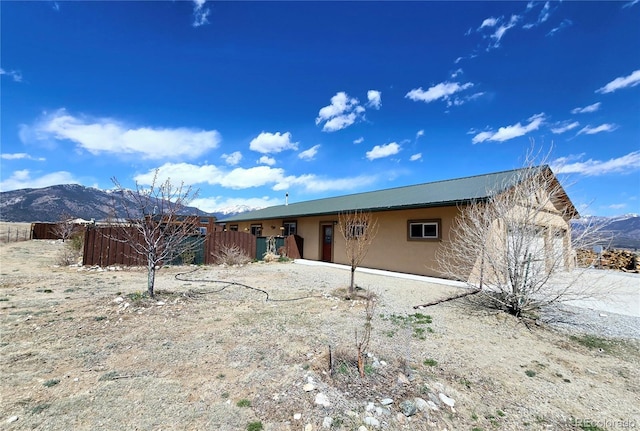 rear view of property with stucco siding, fence, and a mountain view