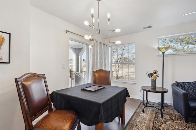 dining room featuring an inviting chandelier, baseboards, visible vents, and wood finished floors