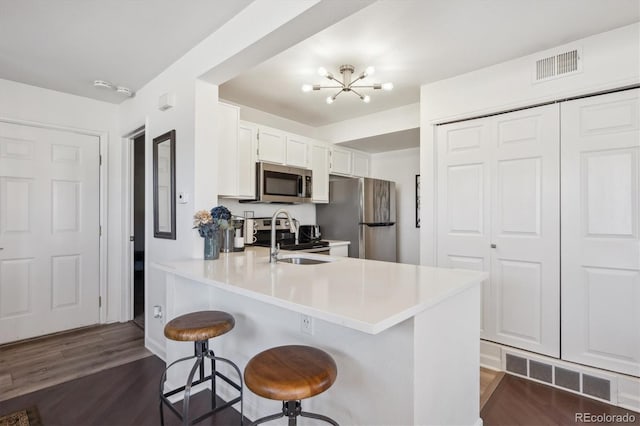 kitchen featuring dark wood-style flooring, visible vents, stainless steel appliances, and a sink