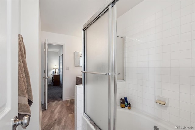 bathroom with a tub to relax in, a shower with door, baseboards, and wood finished floors