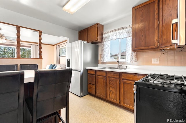 6981 Zuni St, Denver, CO 80221 - kitchen featuring a sink, light countertops, brown cabinetry, freestanding refrigerator, and black gas stove
