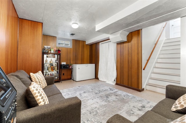 6981 Zuni St, Denver, CO 80221 - living area featuring wooden walls, a textured ceiling, visible vents, and stairway