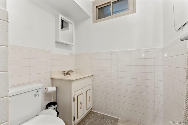 6981 Zuni St, Denver, CO 80221 - bathroom with toilet, tile walls, wainscoting, and vanity