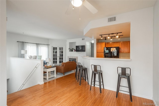 8707 E Florida Ave Unit 510, Denver, CO 80247 - kitchen with brown cabinets, track lighting, a kitchen bar, visible vents, and black fridge with ice dispenser