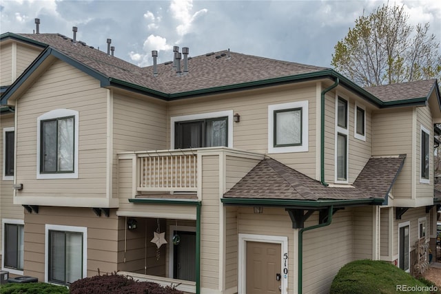 8707 E Florida Ave Unit 510, Denver, CO 80247 - back of property with a garage, a shingled roof, central air condition unit, and a balcony