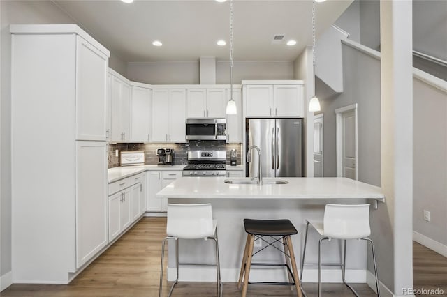 kitchen with sink, a kitchen breakfast bar, white cabinets, and stainless steel appliances