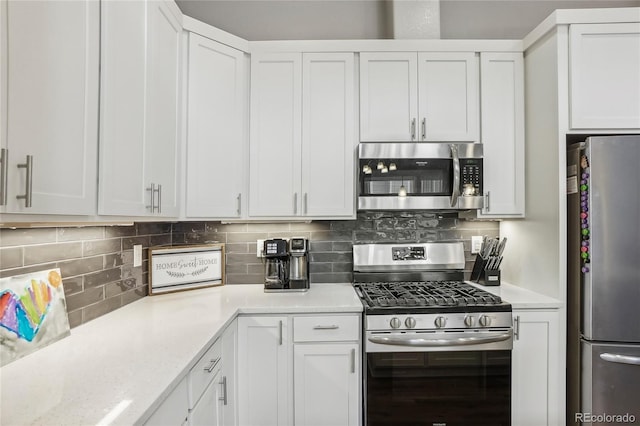 kitchen with light stone countertops, backsplash, white cabinetry, and appliances with stainless steel finishes