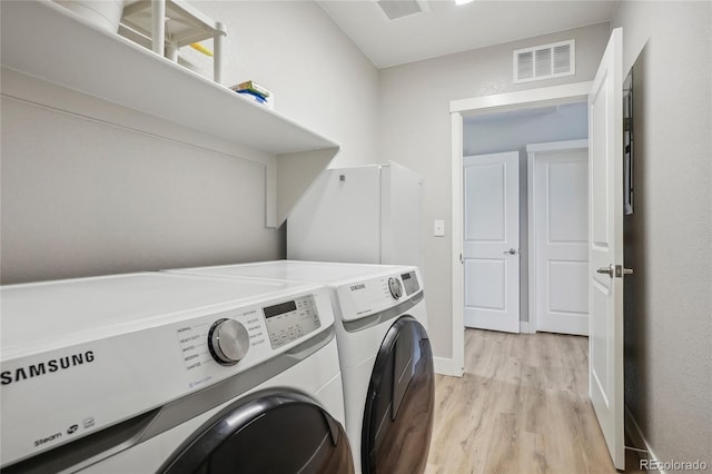 laundry area featuring washing machine and dryer and light wood-type flooring