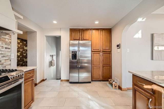 kitchen featuring light stone countertops, appliances with stainless steel finishes, and light tile patterned floors