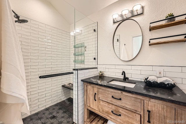 bathroom with tasteful backsplash, lofted ceiling, vanity, and an enclosed shower