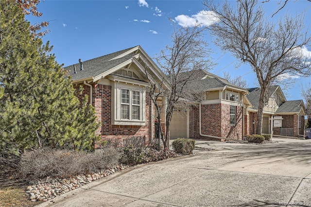 view of front facade with a shingled roof, brick siding, driveway, and an attached garage