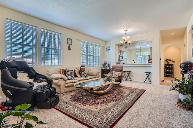 living area featuring a chandelier, carpet floors, a textured ceiling, and baseboards