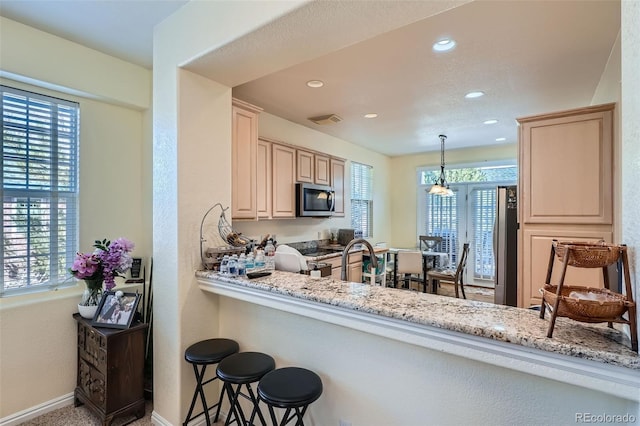 kitchen with light stone counters, stainless steel microwave, plenty of natural light, and visible vents