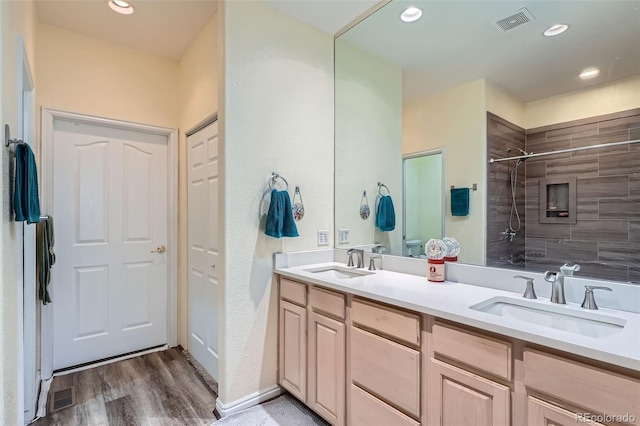 full bathroom with visible vents, a sink, and tiled shower