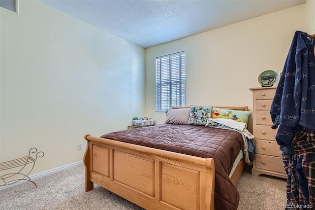 bedroom featuring a textured ceiling, carpet floors, visible vents, and baseboards