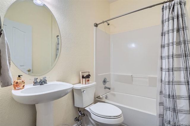 bathroom with a textured wall, shower / bath combo with shower curtain, and toilet