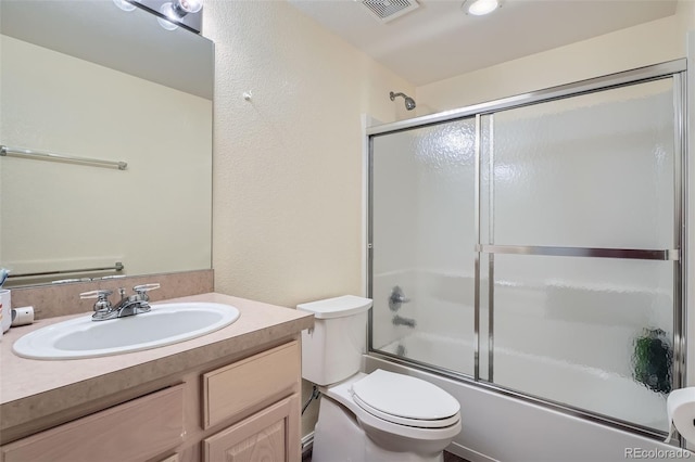 full bathroom with visible vents, bath / shower combo with glass door, a textured wall, toilet, and vanity