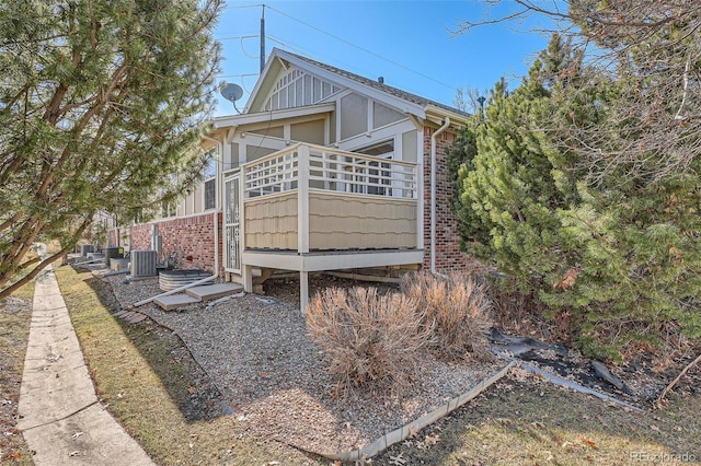 view of home's exterior featuring board and batten siding, cooling unit, and brick siding