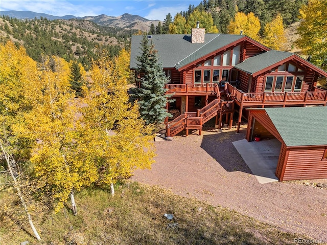 3115 State Highway 9, Guffey, CO 80820 - back of property featuring a deck with mountain view, roof with shingles, log siding, a chimney, and stairs