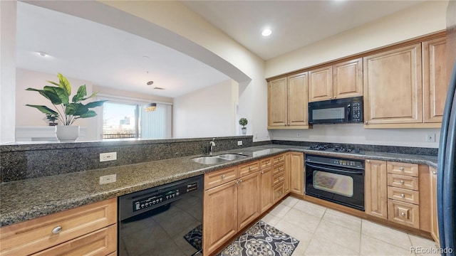 kitchen with light tile patterned floors, recessed lighting, a sink, black appliances, and dark stone countertops