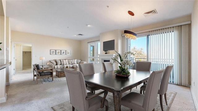 dining room with a fireplace, visible vents, and light colored carpet