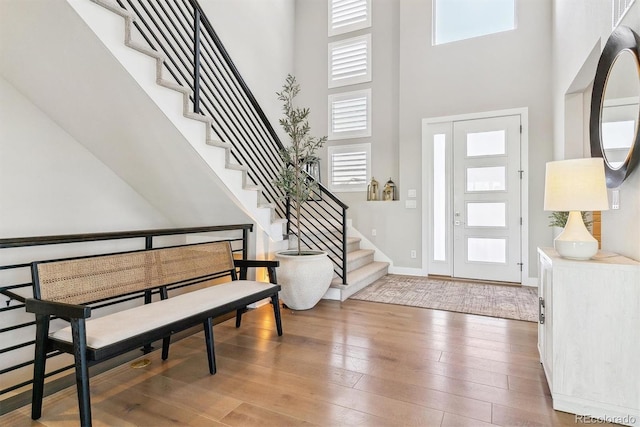 foyer entrance with a high ceiling, wood-type flooring, and a healthy amount of sunlight