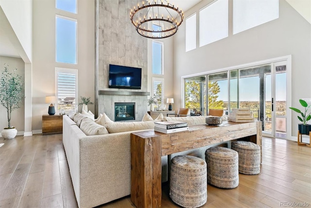 living room featuring hardwood / wood-style flooring, a healthy amount of sunlight, a large fireplace, and a chandelier