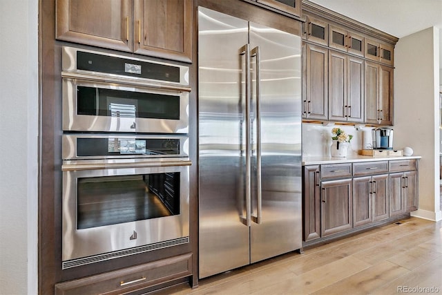 kitchen with appliances with stainless steel finishes and light hardwood / wood-style flooring